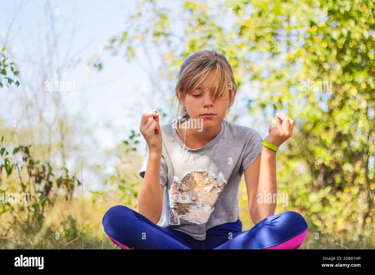 Defocus caucasian preteen girl practicing yoga in park, forest, outdoor, outside. Meditation and concentration. Wellness healthy lifestyle. Portrait o Stock Photo