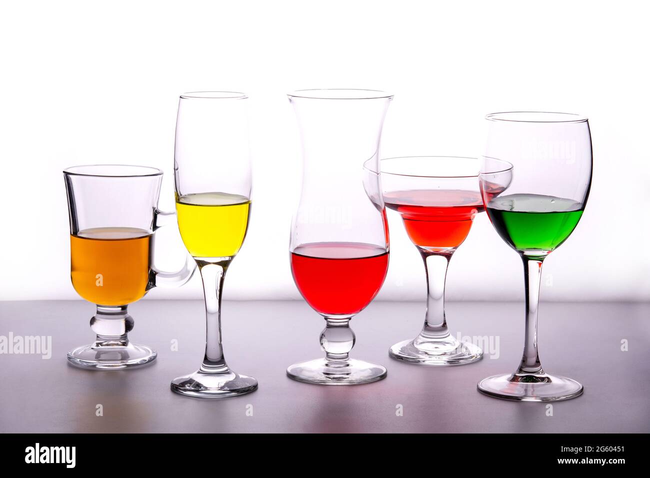 Different types of crystal glasses with colorful liquid inside Stock
