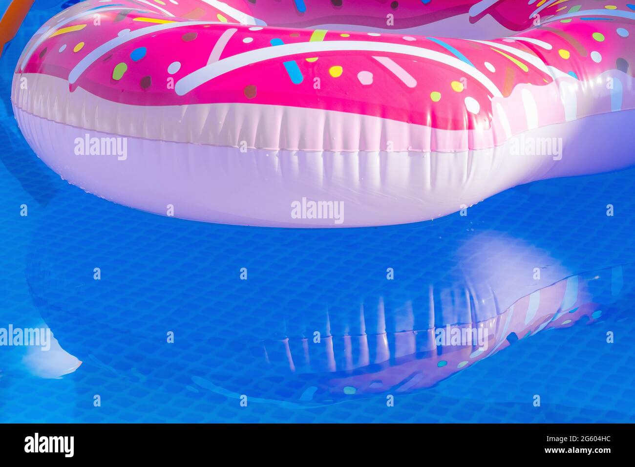 A colourful inflatable plastic ring floating in an outdoor pool Stock