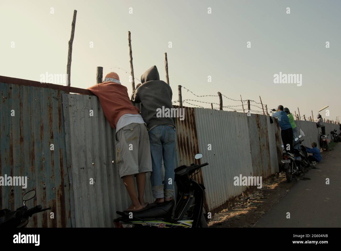Recreational fishers standing on motorcycles to fish on a pond located in a closed area in Jakarta coastal zone. Jakarta, Indonesia. Stock Photo