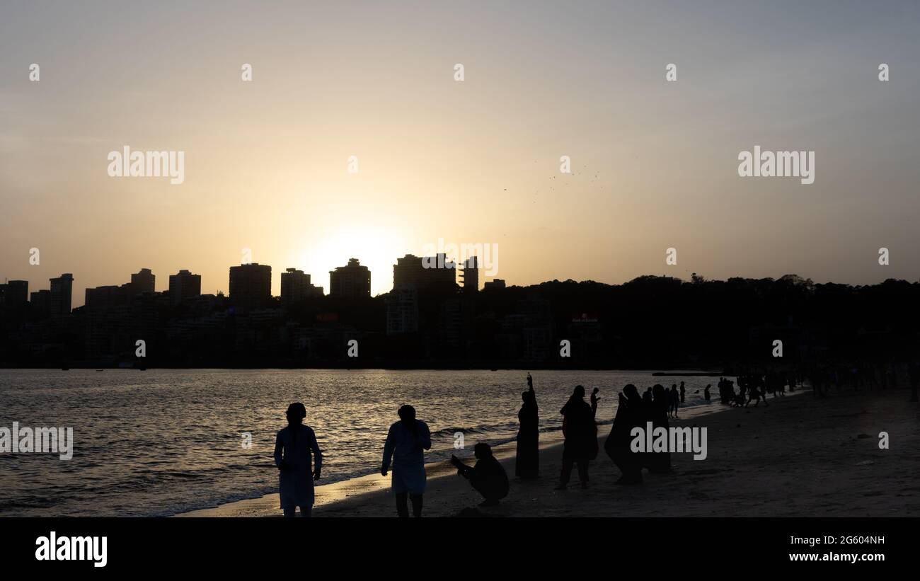 Silhouettes of people and skyscrapers during sunset at Marine drive Beach in Mumbai Maharashtra India on 2 April 2021 Stock Photo