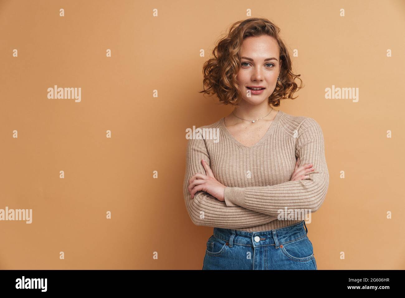 Young ginger woman with wavy hair posing and looking at camera isolated ...