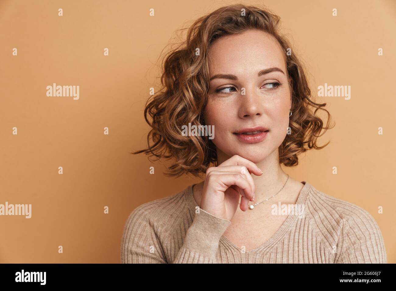 Young ginger woman with wavy hair posing and looking aside isolated ...