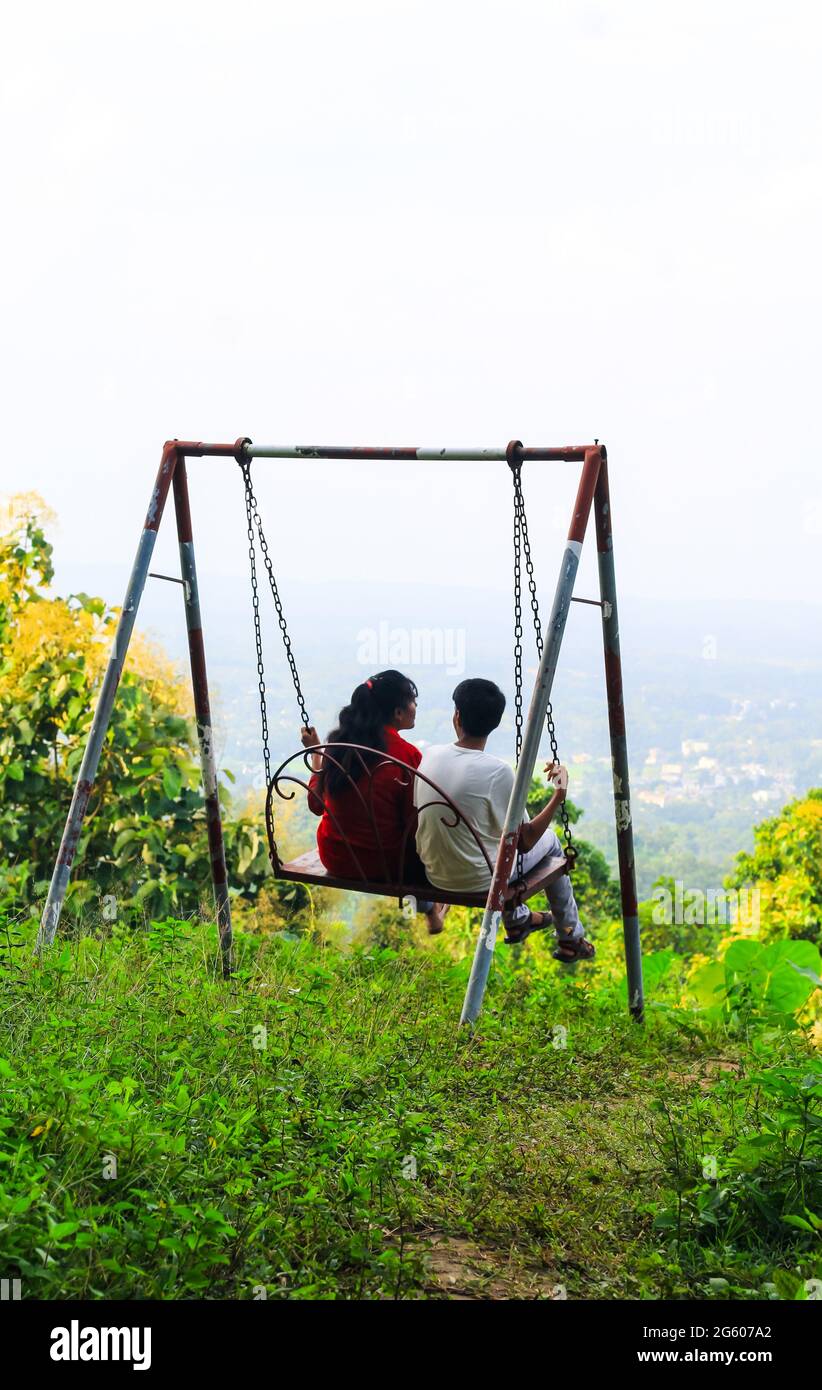 Romantic couple swinging on swings over the green mountain landscape