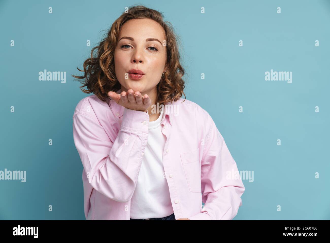 Young ginger woman with wavy hair blowing air kiss at camera isolated