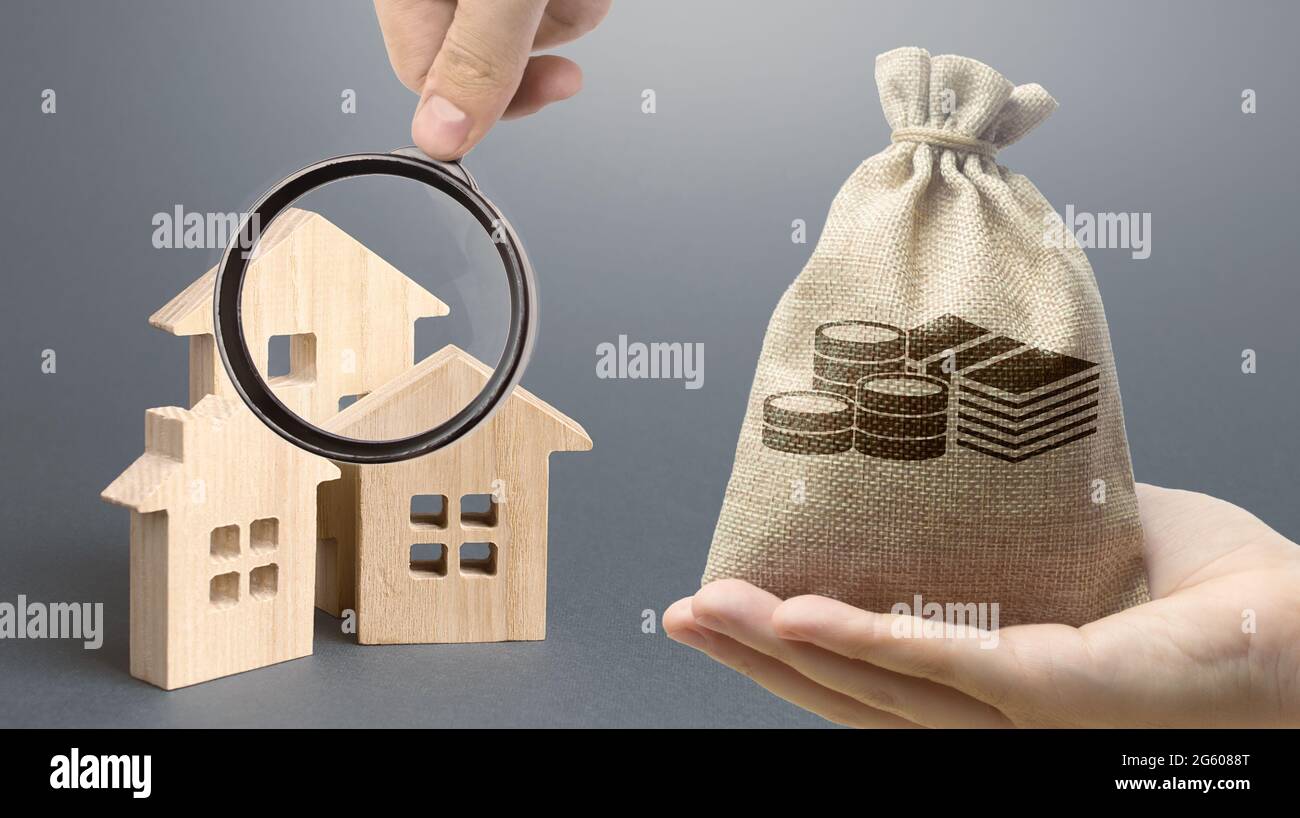 Money bag, wooden houses on a gray background. Buy purchase and sale of
