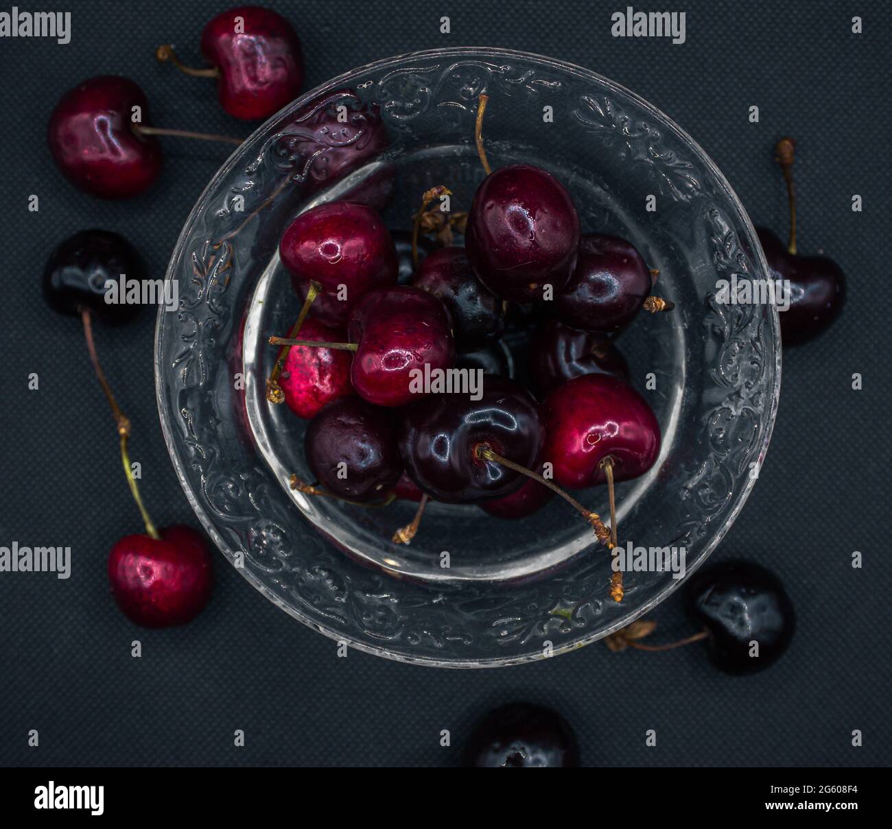 Cherries with water drops in a transparent glass jar on a black table. Ripe cherries. Sweet red cherry. top view. Rustic style. fruit wallpaper Stock Photo