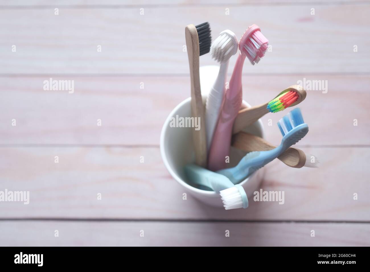 colorful toothbrushes in white mug against a wall Stock Photo - Alamy