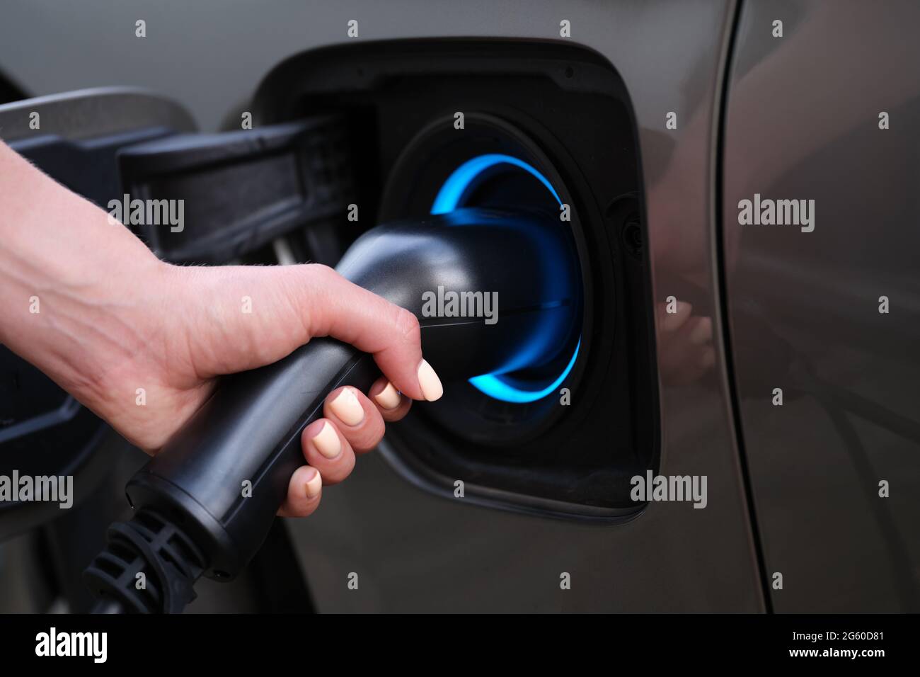 Woman charging car using electric plug closeup Stock Photo