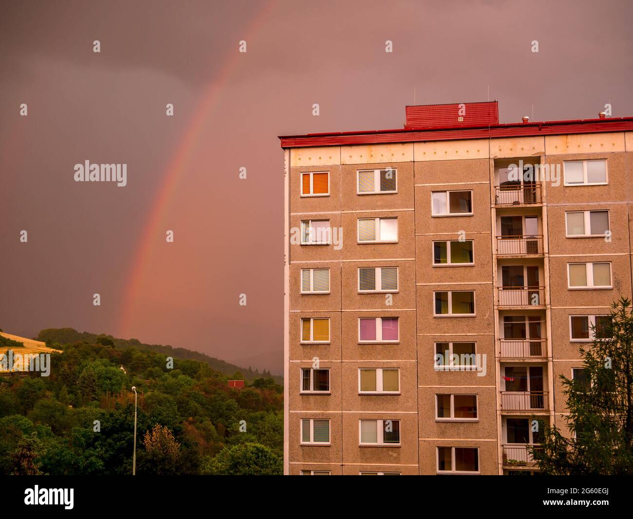 Rainbow over the house with dense rain clouds in the background Stock Photo