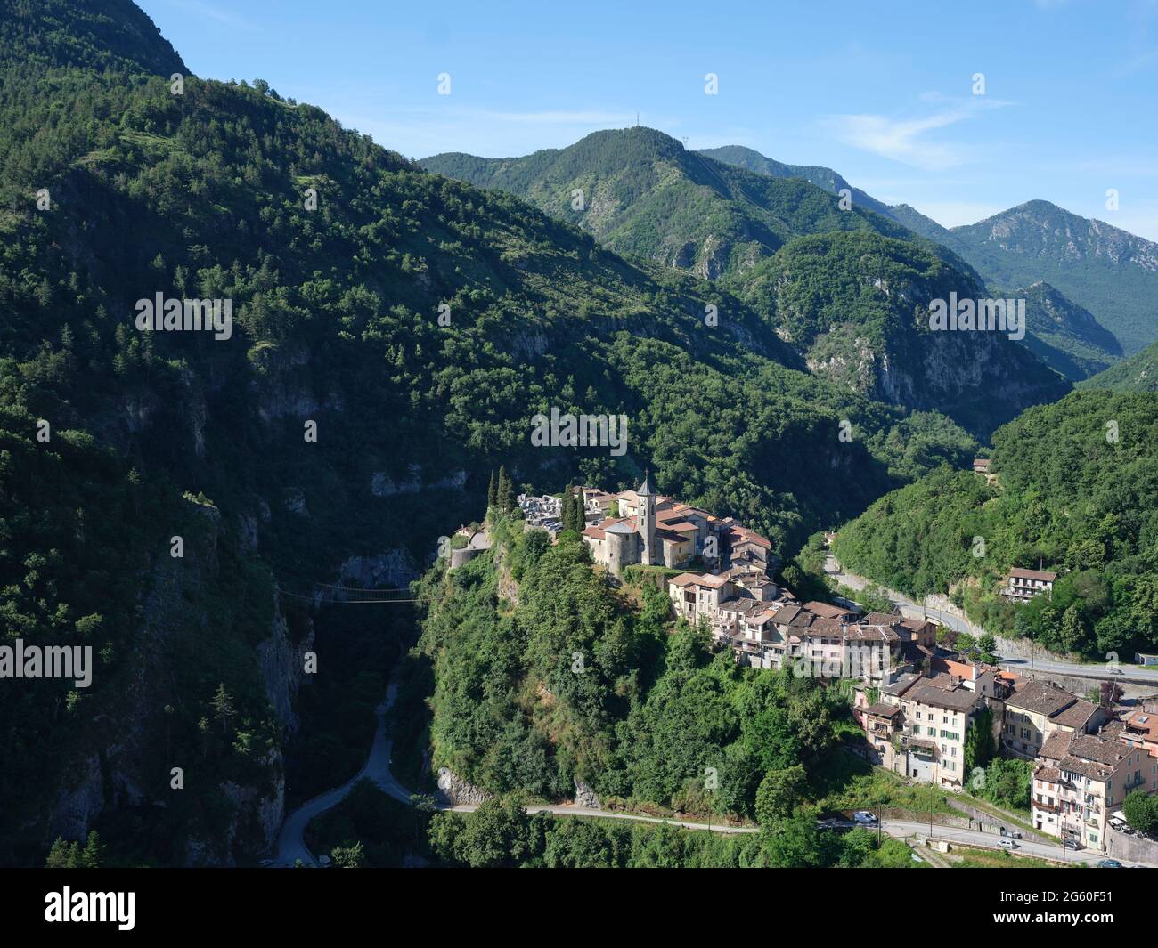 AERIAL VIEW. Perched village of Lantosque in a deep and narrow wooded valley, looking downstream. Vésubie Valley, Alpes-Maritimes, France. Stock Photo