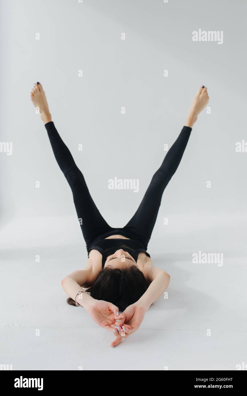 barefoot armenian woman in black leggings practicing yoga in rejuvenation pose on white Stock Photo