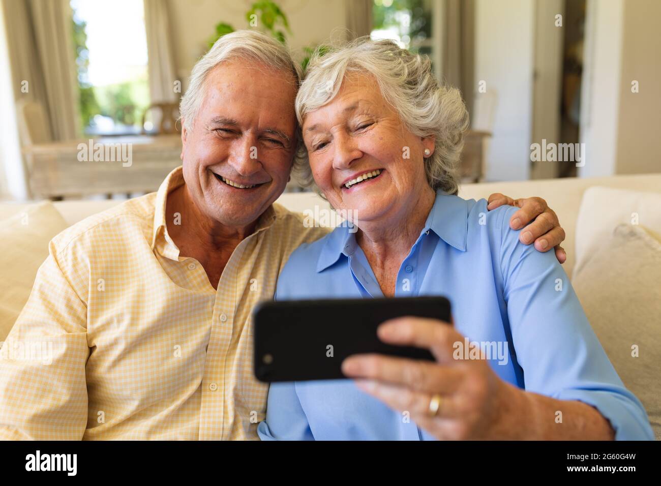 Senior caucasian couple sitting on sofa having video call using ...