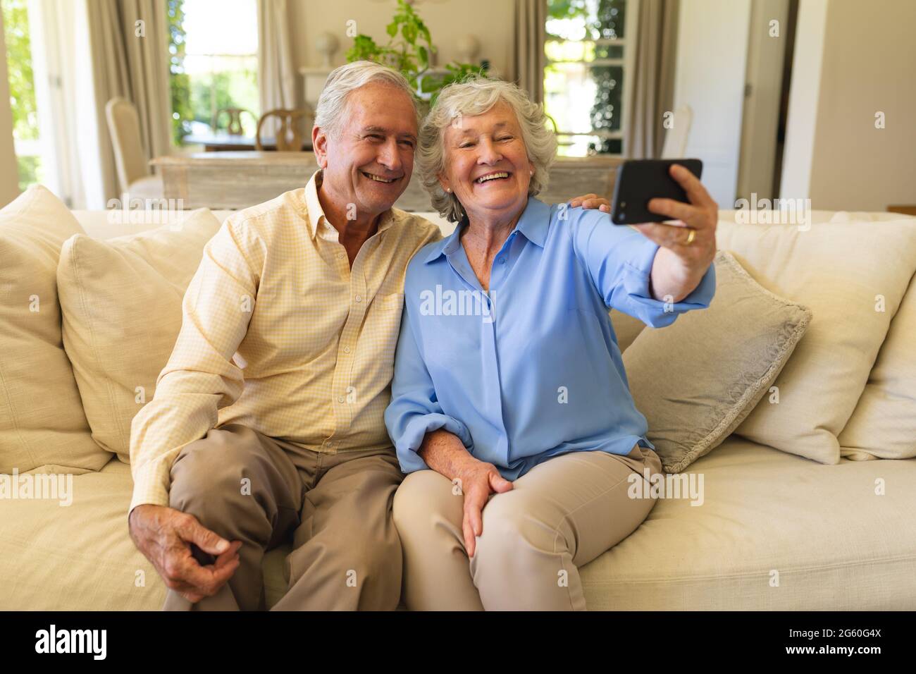 Senior caucasian couple sitting on sofa having video call using ...