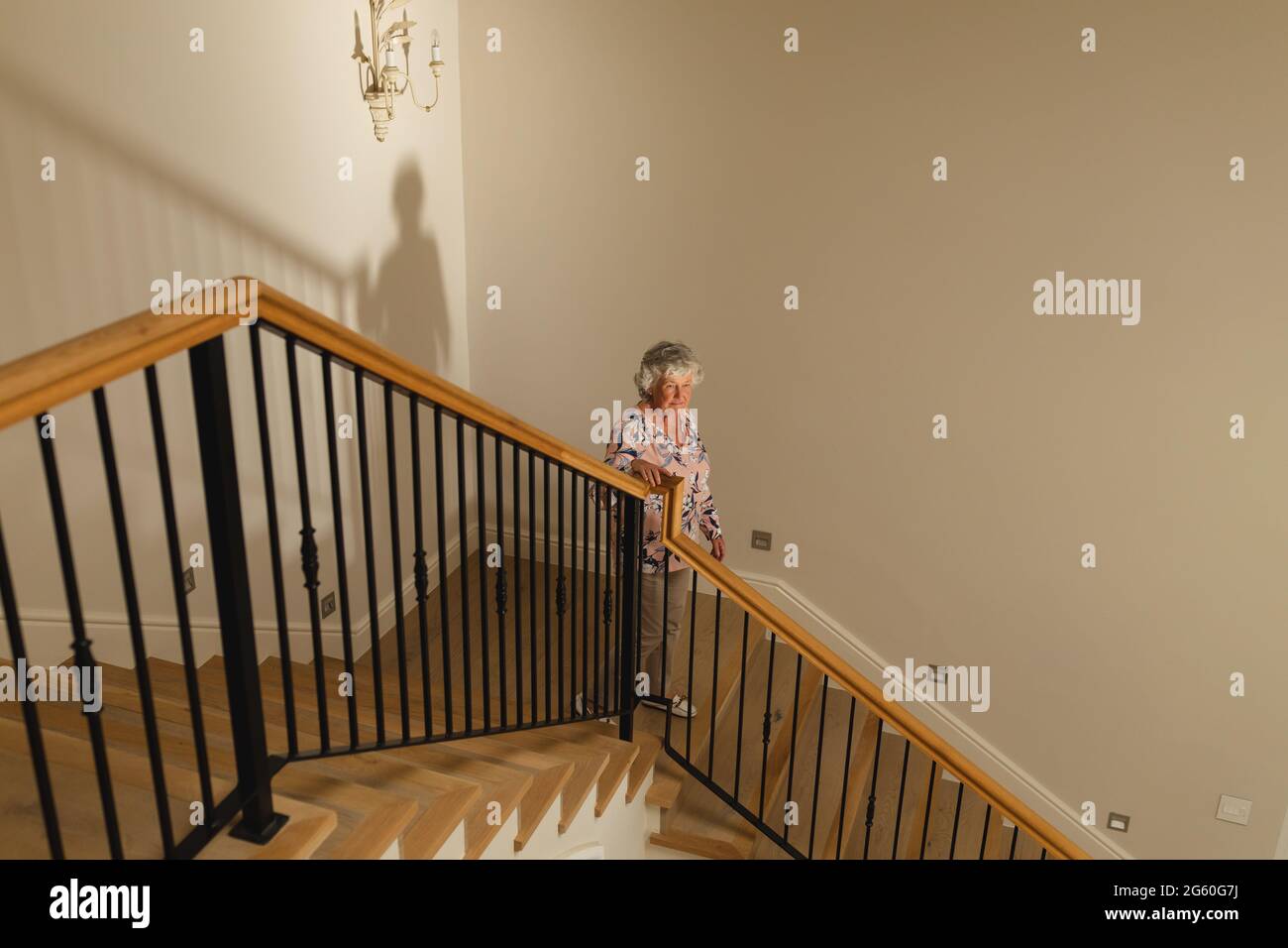 Woman Using Handrail Senior caucasian woman holding handrail walking down stairs Stock Photo ...