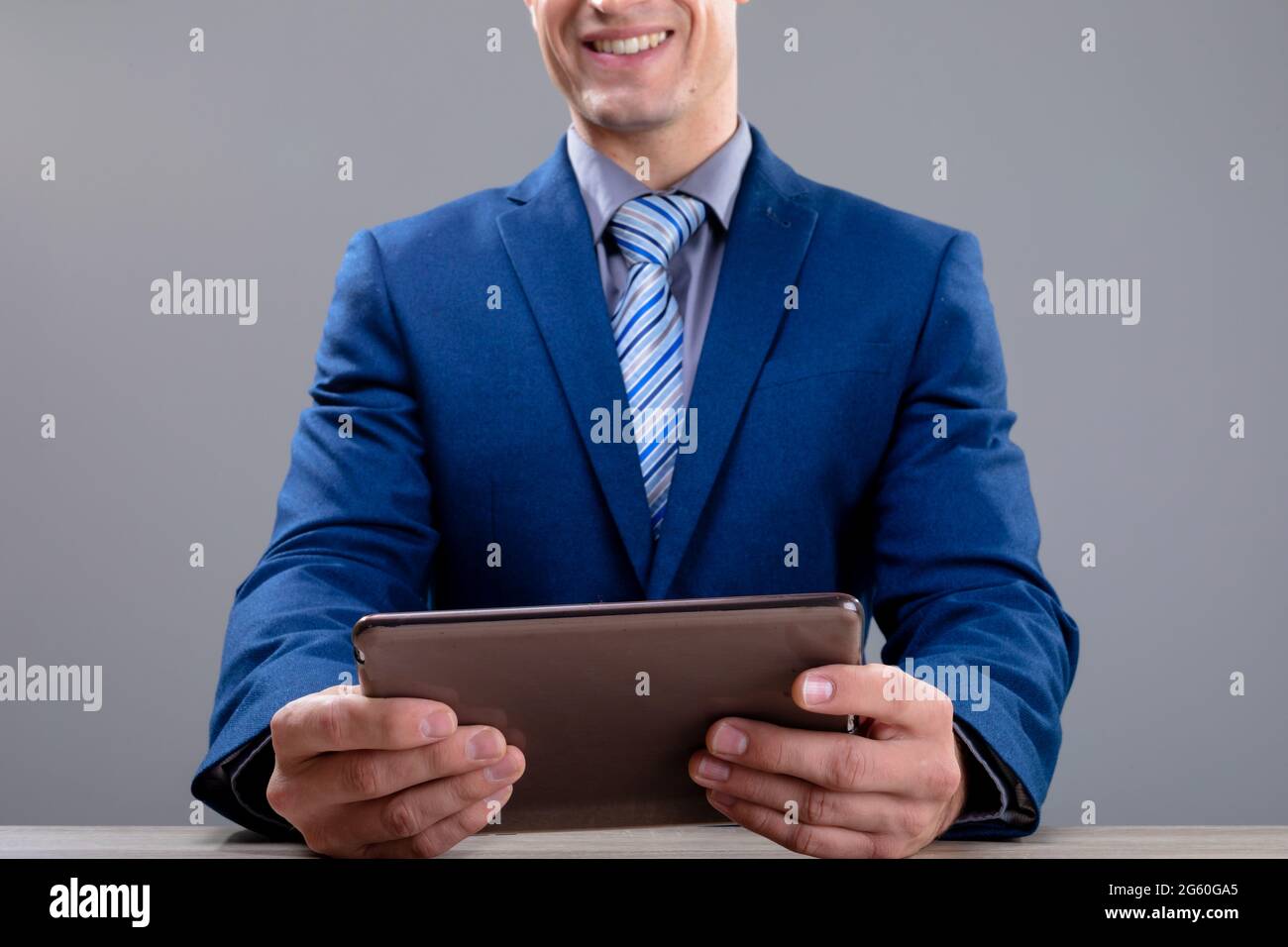 Smiling caucasian businessman using tablet, isolated on grey background Stock Photo