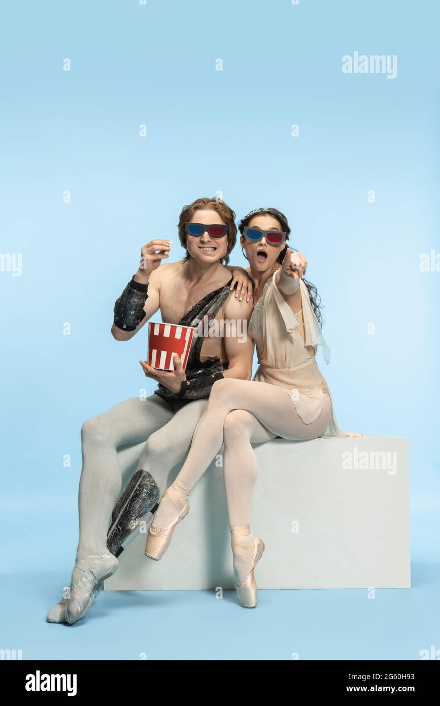 Movie lover. Young couple of ballet dancers in ancient Rome costums at blue studio. Stock Photo