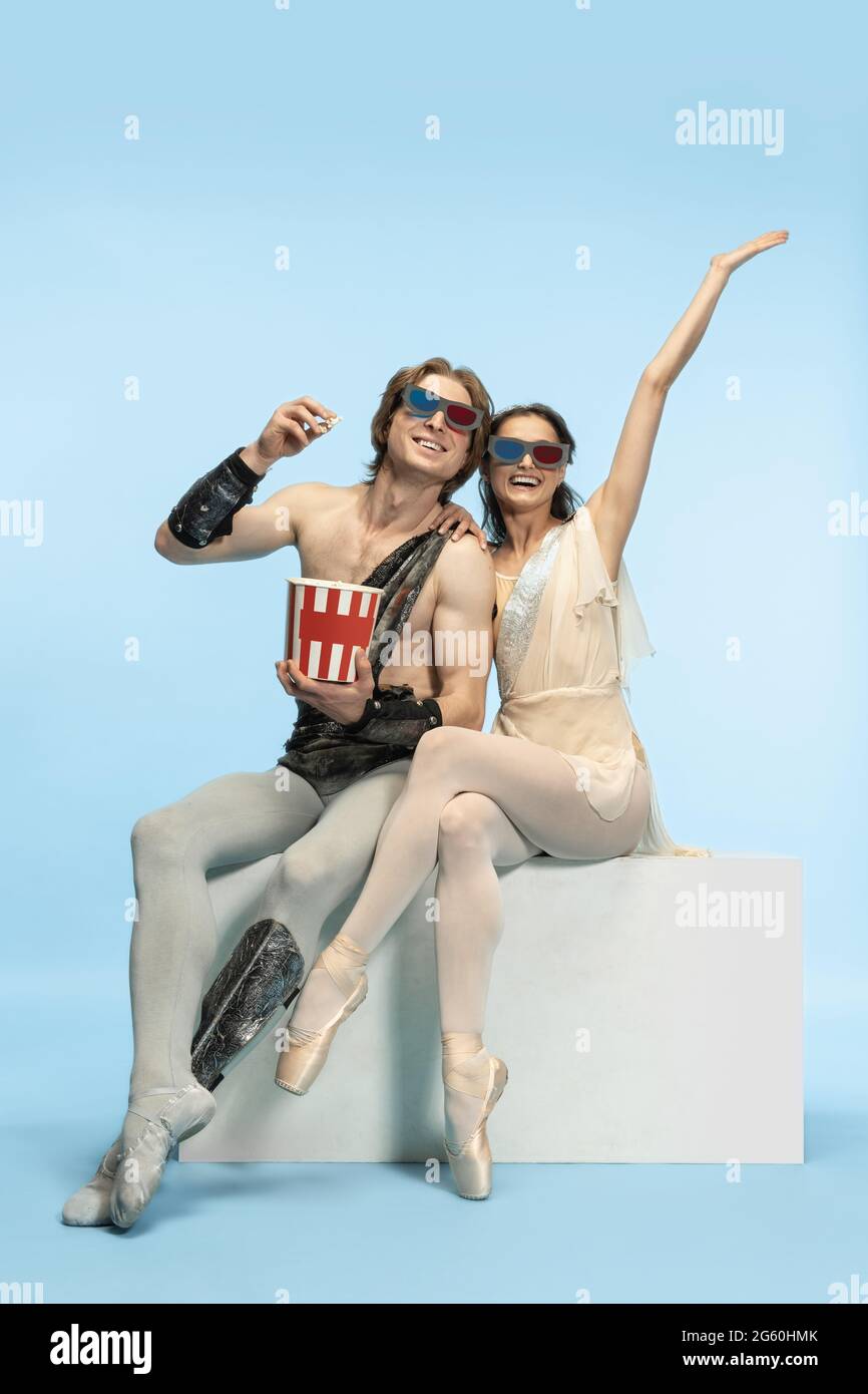 Movie lover. Young couple of ballet dancers in ancient Rome costums at blue studio. Stock Photo