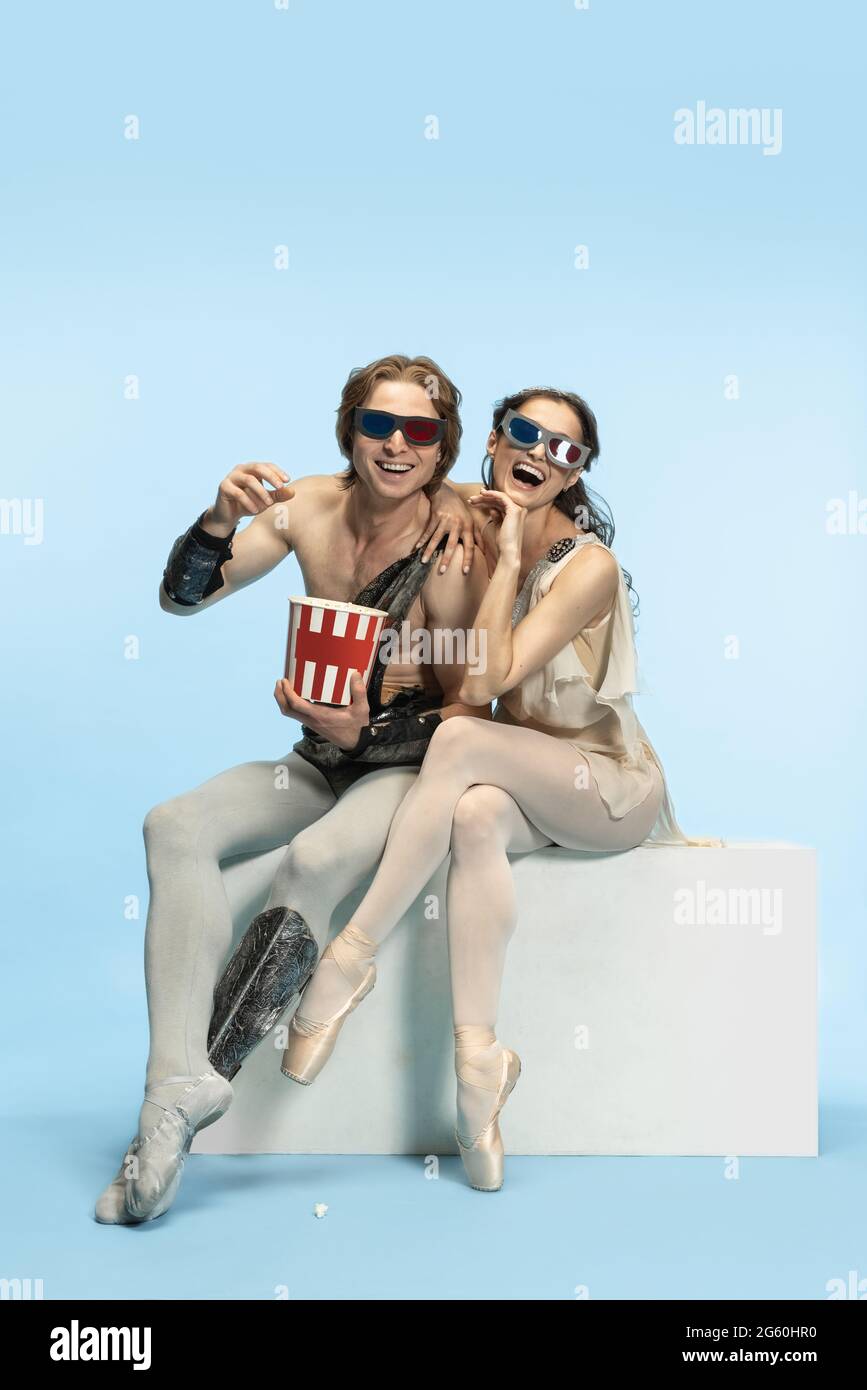 Movie lover. Young couple of ballet dancers in ancient Rome costums at blue studio. Stock Photo