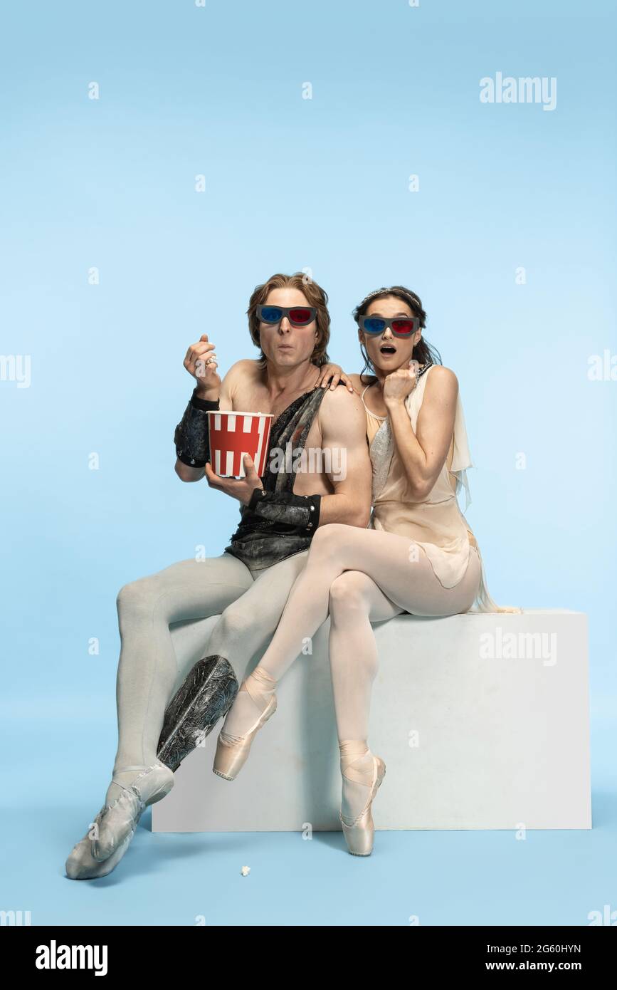 Movie lover. Young couple of ballet dancers in ancient Rome costums at blue studio. Stock Photo