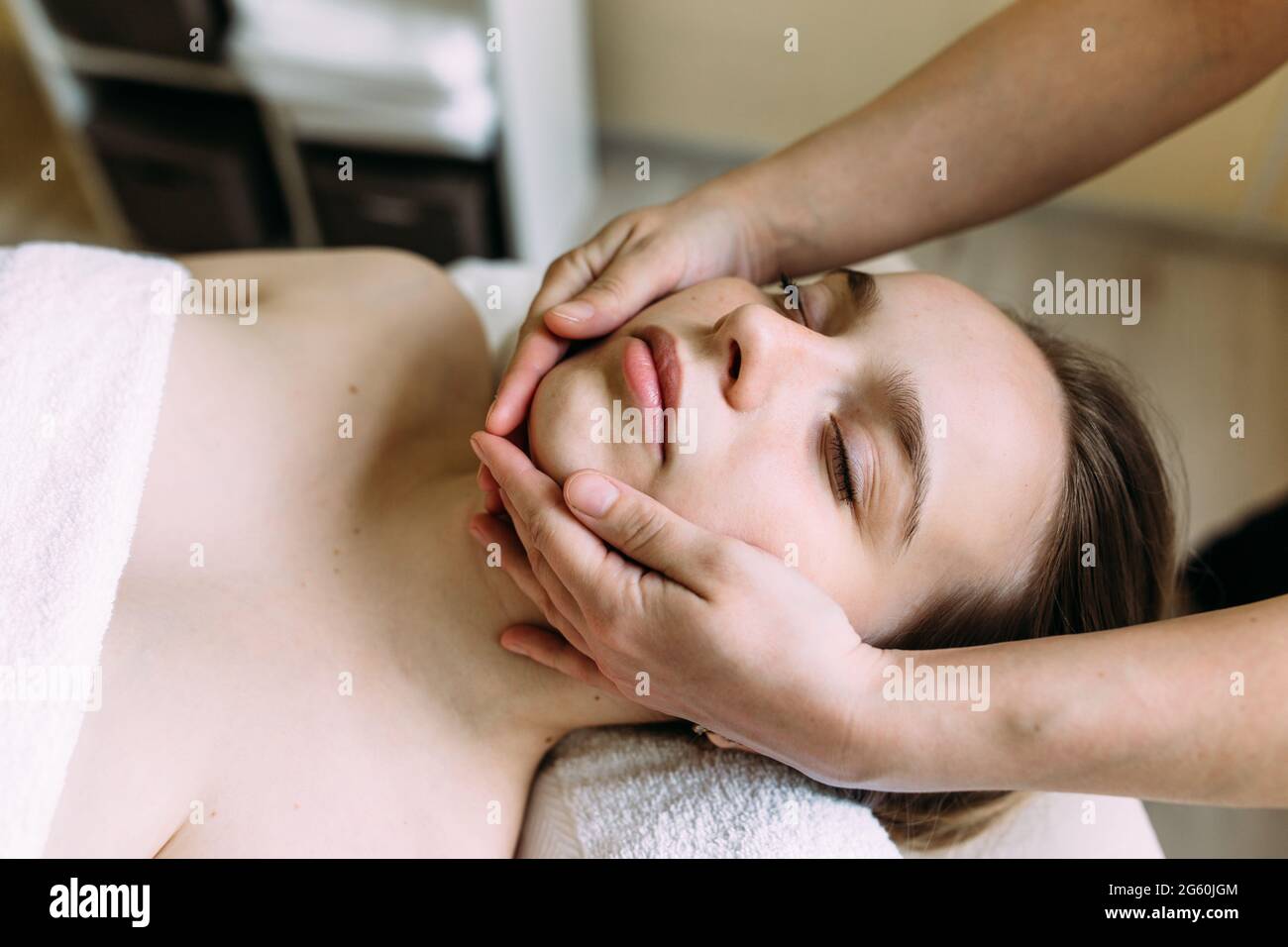 Masseur doing massage on a woman's face at the spa. Stock Photo
