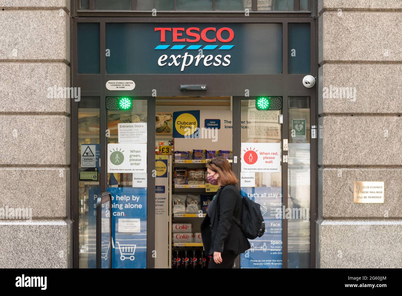 A woman wearing a mask walks past a Tesco Express store in London.In recent  weeks, the number of confirmed covid cases in the UK has been on the rise,  and has reached