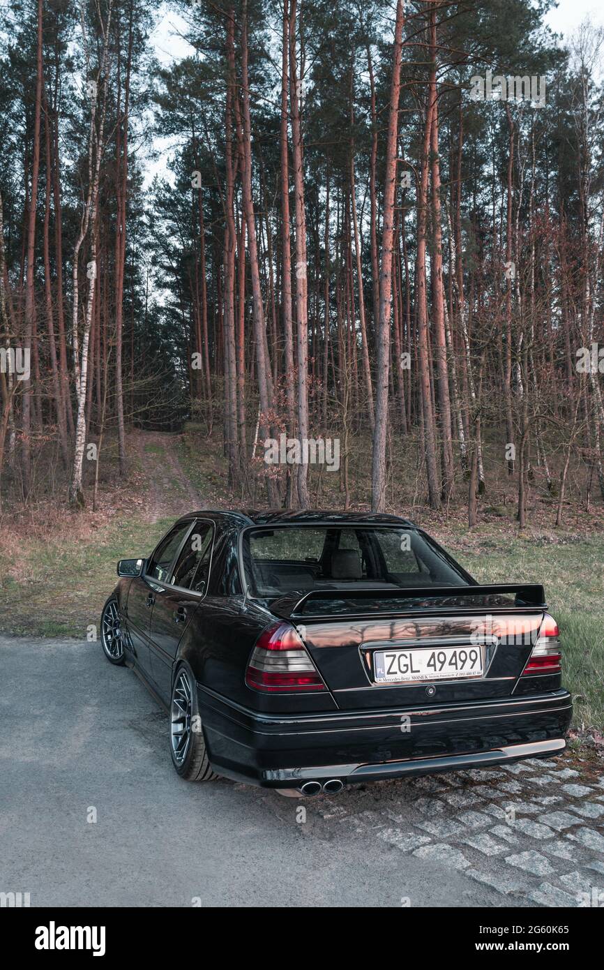 https://c8.alamy.com/comp/2G60K65/goleniow-poland-april-20th-2021-old-black-tuned-mercedes-benz-c-class-w202-model-near-forest-compact-luxury-sedan-icon-from-the-90s-vertical-2G60K65.jpg