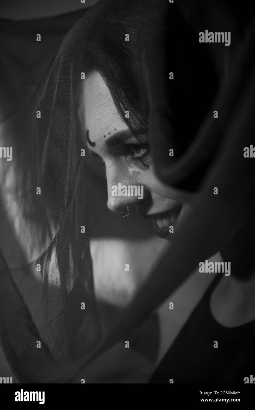 Profile of a woman in a black veil. Costume Dead bride for Halloween. Portrait of an evil grinning Witch in front of a coven. Stock Photo