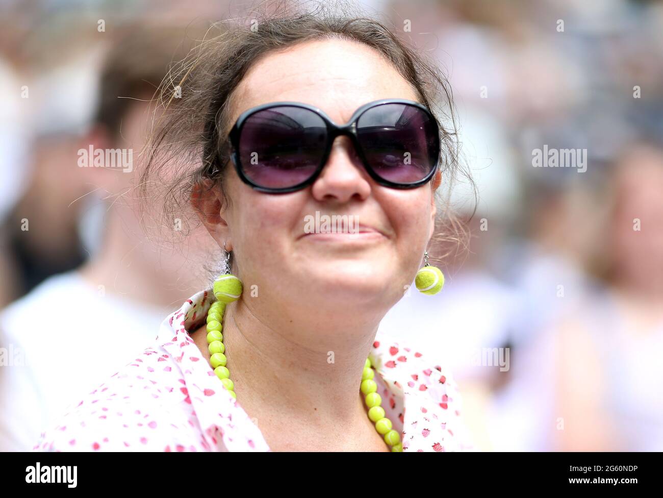 A spectator with tennis ball earrings watches the match between Cameron  Norrie and Alex Bolt on court 1 on day four of Wimbledon at The All England  Lawn Tennis and Croquet Club,