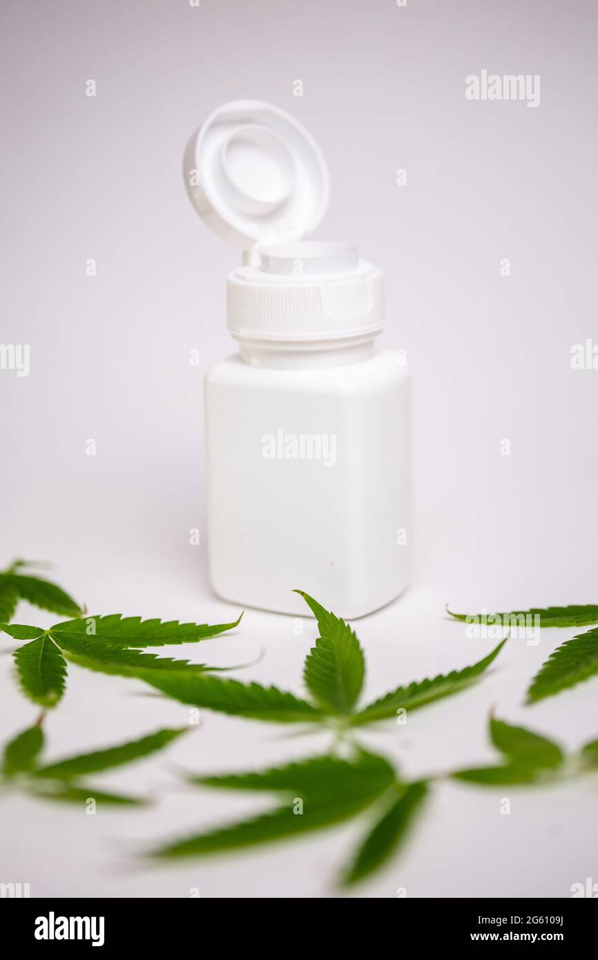 white jar and cannabis leaves on a white background Stock Photo