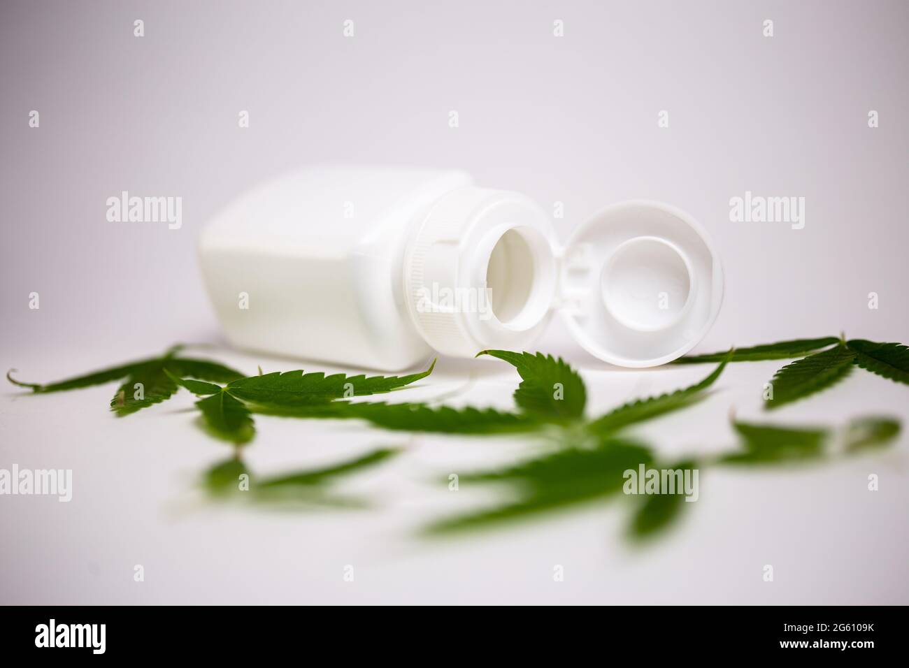 white jar with cannabis leaves on a white background. Stock Photo