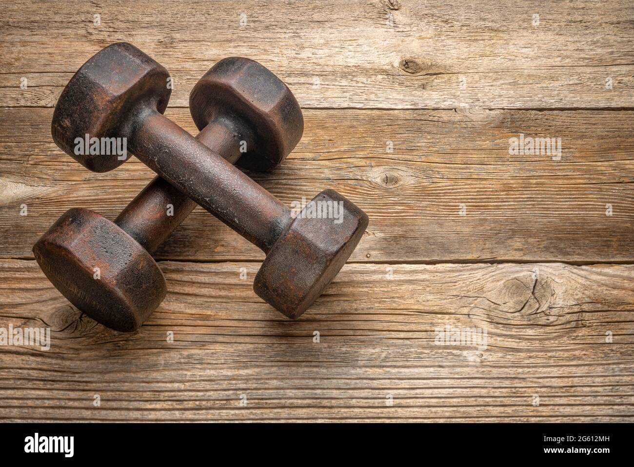 a pair of vintage iron rusty dumbbells on a grained barn wood background  with a copy space, fitness concept Stock Photo - Alamy