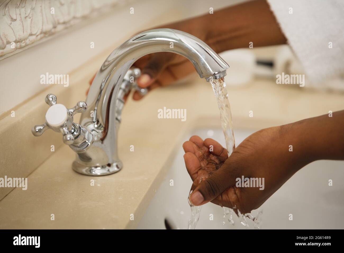 Midsection of african american woman in bathroom wearing bathrobe washing hands in basin Stock Photo