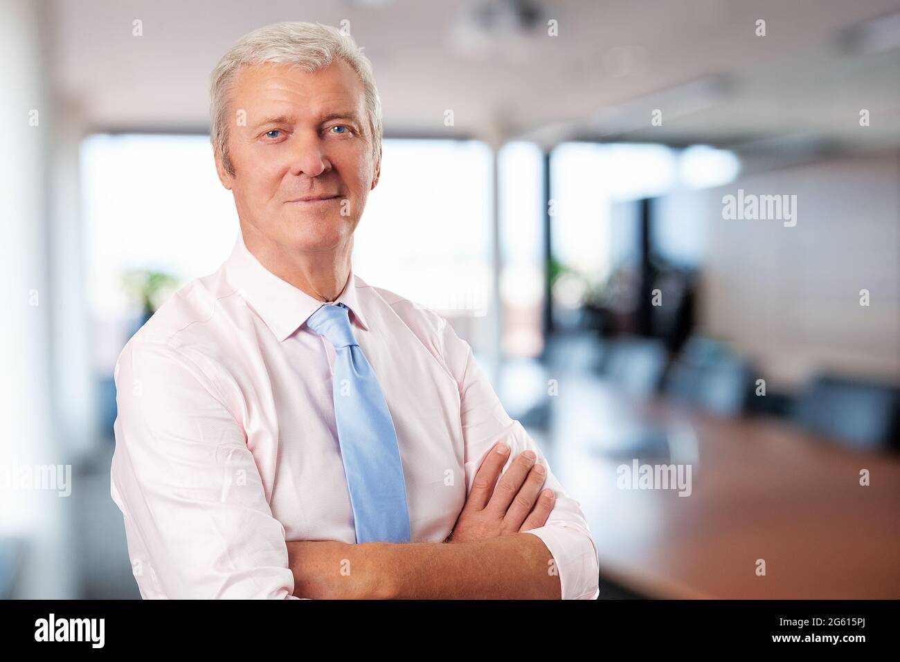 Portrait of a senior man standing with arms crossed at isolated white ...