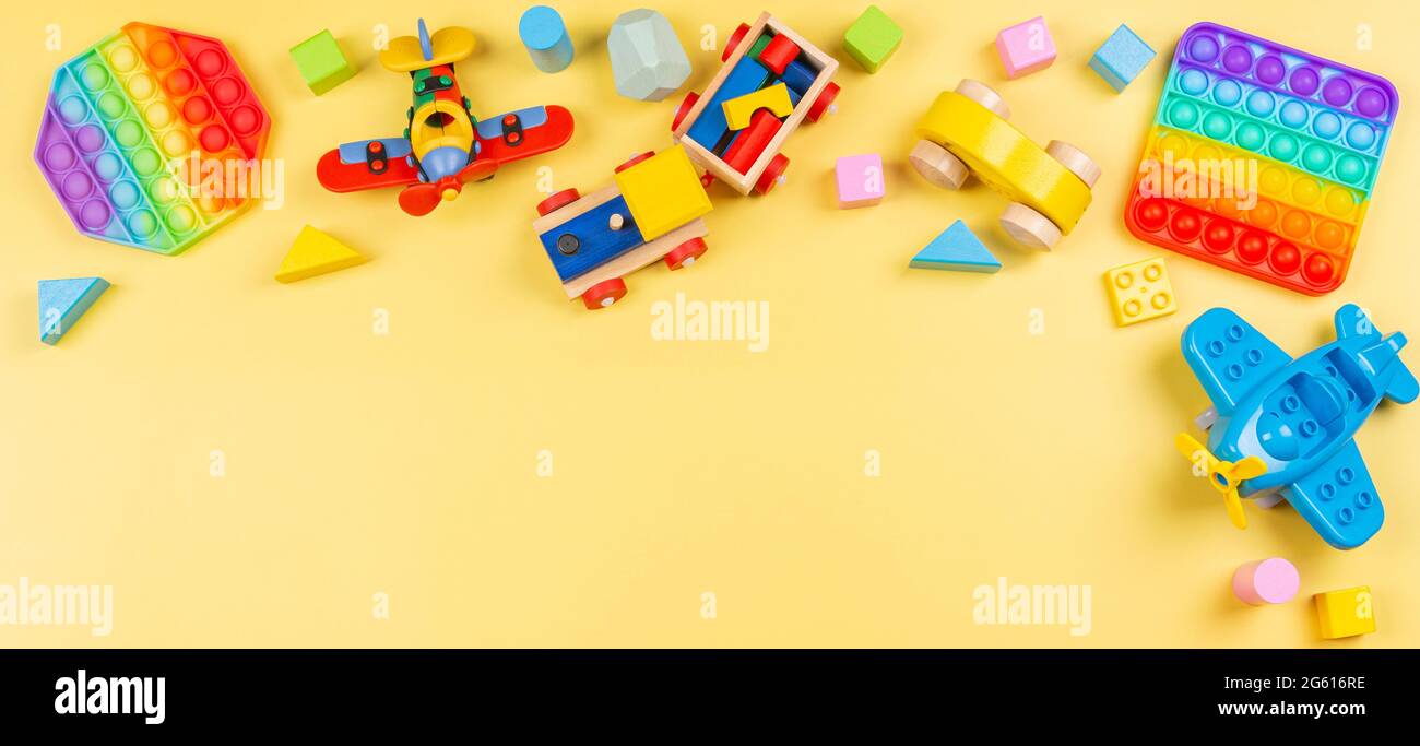 Baby kid toys banner background with wooden blocks, train, car, plane, pop  it fidget toy on yellow background. Top view, flat lay, copy space Stock  Photo - Alamy