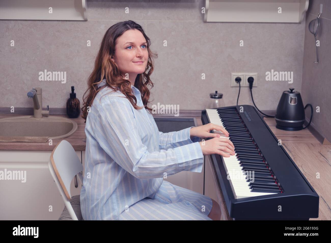 Happy woman sitting at home kitchen at musical instrument and smiling ...