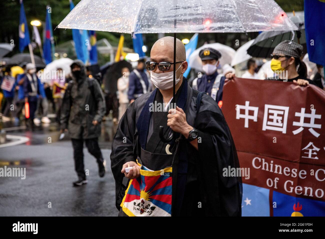 Tokyo, Japan. 01st July, 2021. A monk with the Tibet flag holding an umbrella, during the demonstration.1st of July marks the 100th anniversary of the founding of the CCP (Chinese Communist Party) and the 24th anniversary of Hong Kong's handover to China. CCP supporters took to the street to celebrate while pro democracy Hong Kong protestors also march through the capital city to express their politic stands. Credit: SOPA Images Limited/Alamy Live News Stock Photo