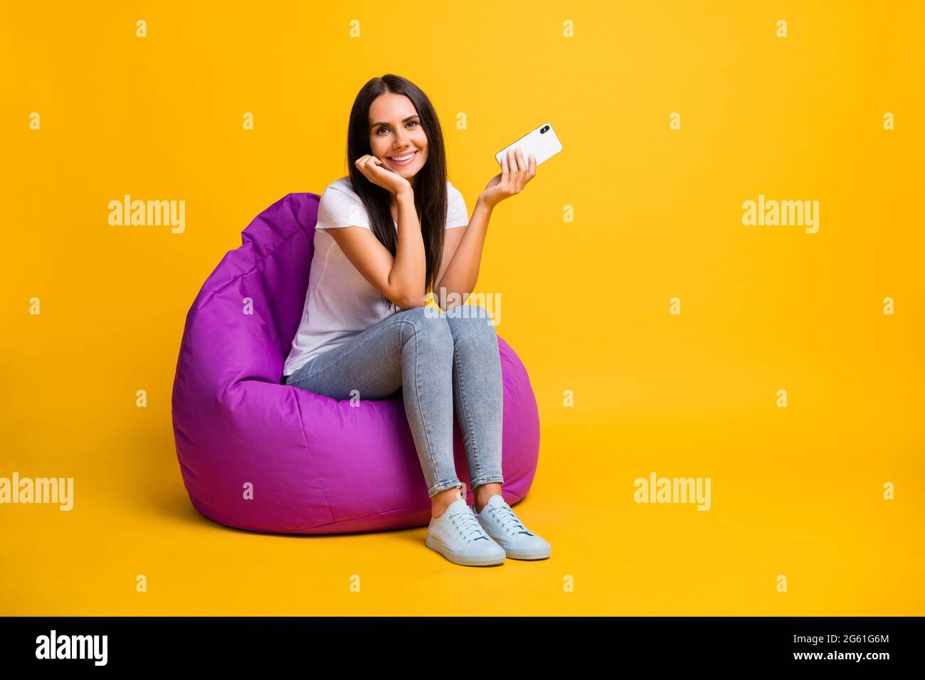 Photo of charming woman dressed white t-shirt sitting bean bag holding ...