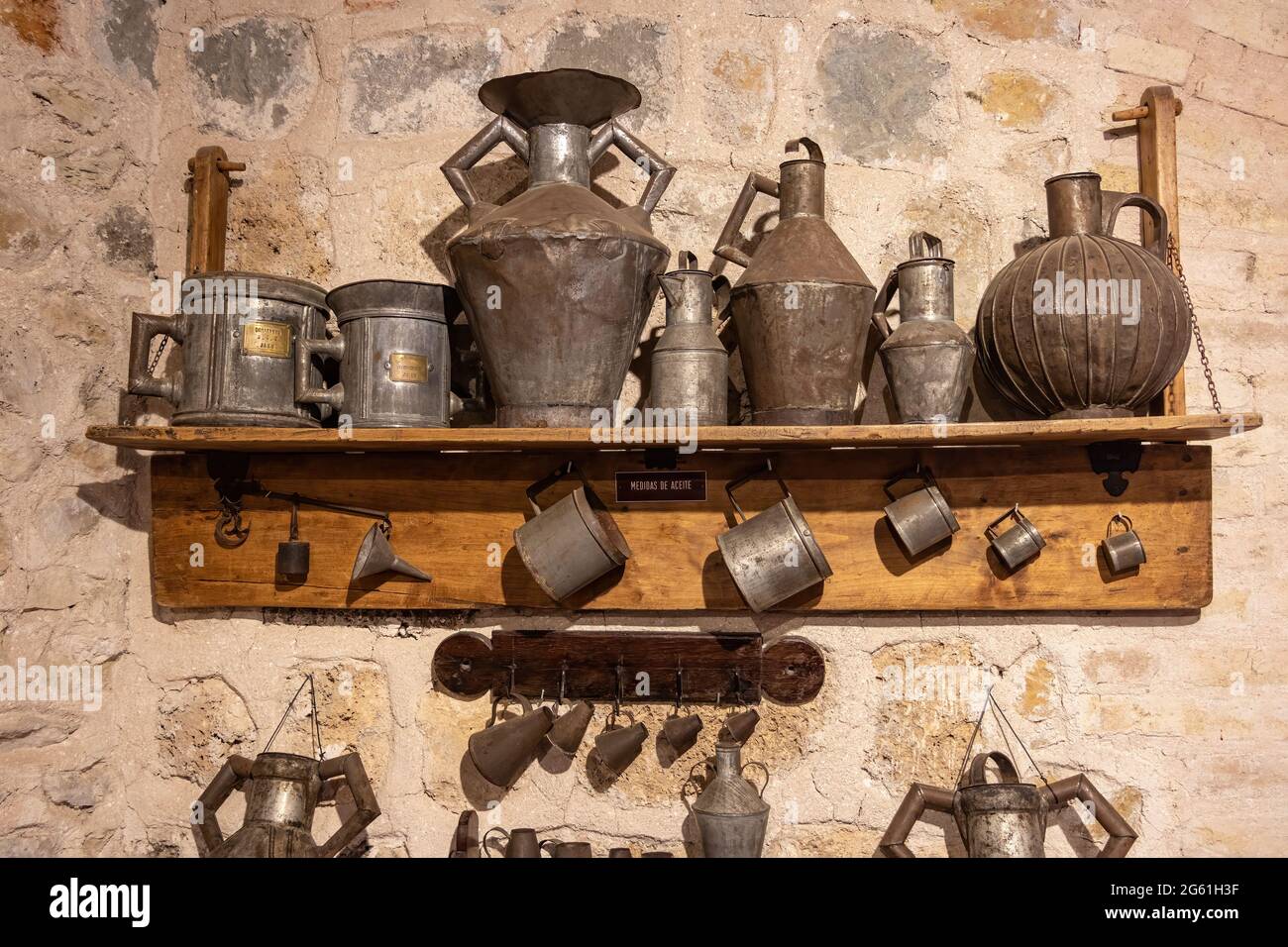 Old measures for oil on a wooden shelf attached to a stone wall inside of the Castillo de la Yedra in Cazorla, A Stock Photo