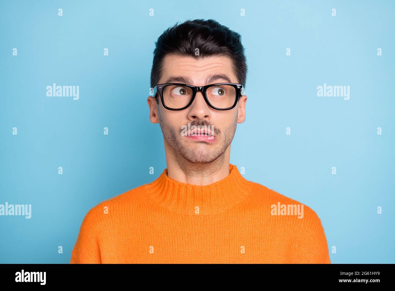 Photo of young weirdo man look staring empty space eyewear wear sweater isolated on blue color background Stock Photo