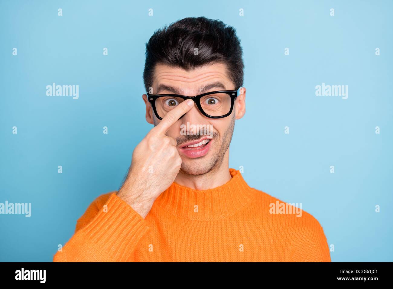Portrait of bearded weirdo person finger touch glasses staring wear pullover isolated on blue color background Stock Photo