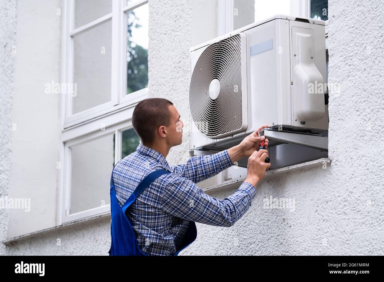 Technician Cleaning And Repairing Air Condition Appliance. AC Unit Maintenance Stock Photo