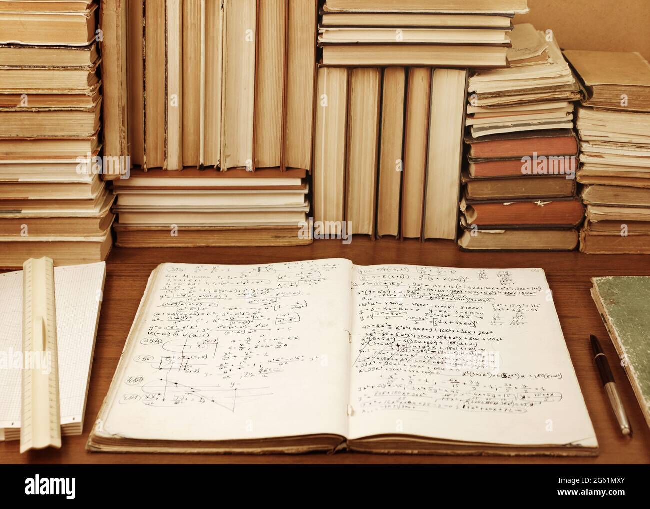 Writing-book with mathematical task solution against a background of books Stock Photo