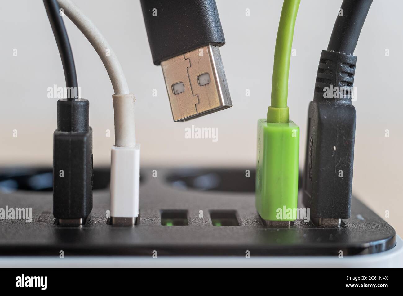 Modern convenient multi-port usb charger for devices. Close-up of inserted multi-colored cables in a power outlet. Macro. Stock Photo