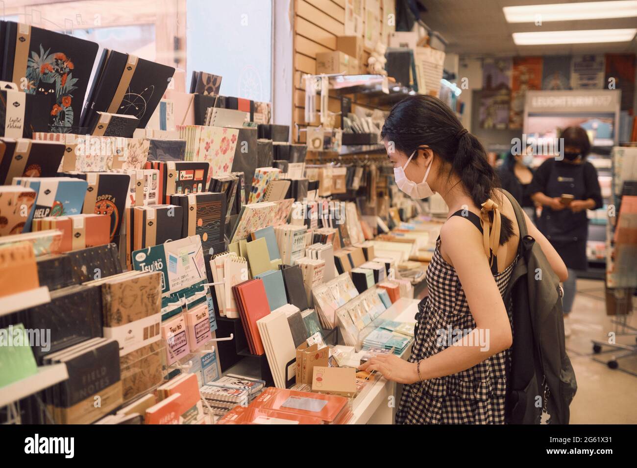 Girl with backpack browsing notebook display at Kinokuniya Bookstore in Little Tokyo. Stock Photo