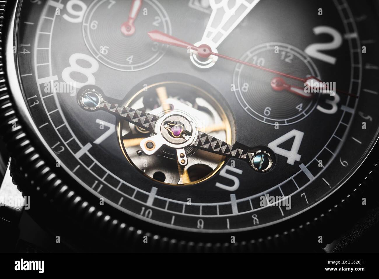 Automatic mechanical wrist watch with black clock face and red arrows, close-up fragment Stock Photo