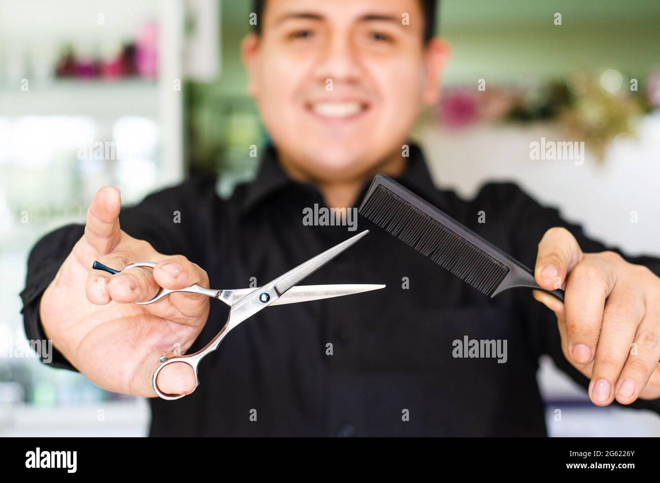 Portrait of an attractive barber holding scissors and comb in his hand. Stock Photo