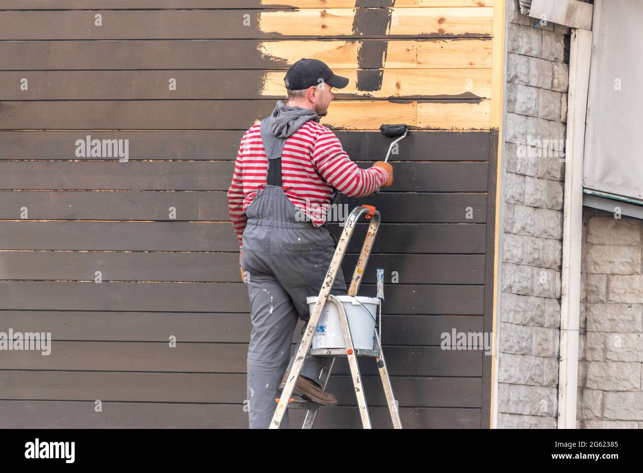 Kiev, Ukraine - April 27, 2021: A man painting wooden wall outside. Stock Photo