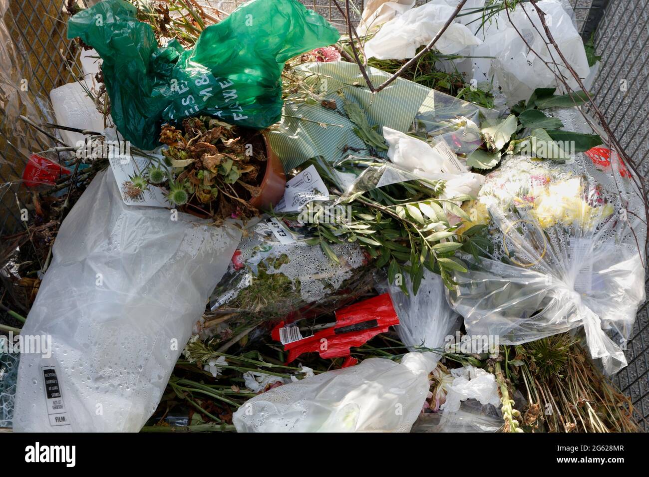 Litter bin in a cemetery full of discarded flowers, and rubbish waste