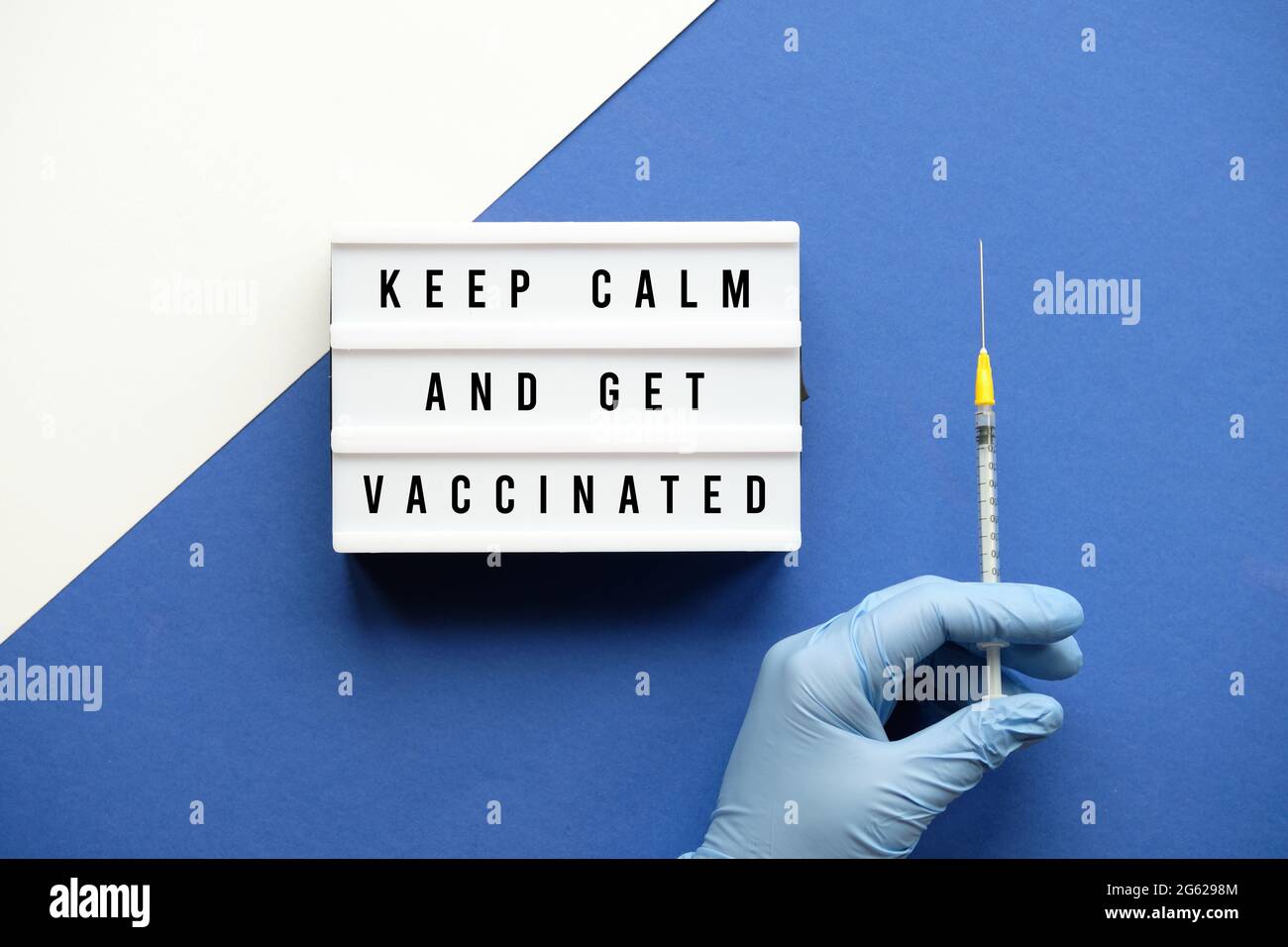 Vaccination motivator concept. Lightbox with text Keep Kalm and Get Vaccinated. Medic hand in glove with COVID 19, measles vaccine syringe. Creative Stock Photo